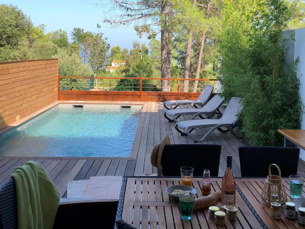 eine Terrasse mit einem Tisch und Stühlen sowie einem Pool in der Unterkunft Les Jardins d Eve Solenzara townhouse with private pool in Favone