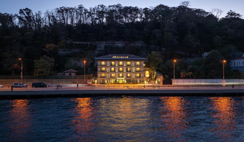 a building is lit up at night next to the water at MFB Tarabya Hotel in Istanbul