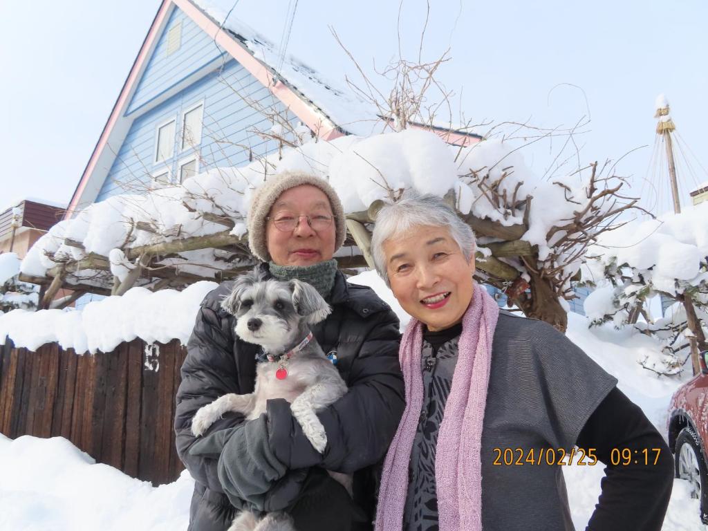 una mujer mayor sosteniendo un perro en la nieve en 民泊 B&B yoshida en Sapporo