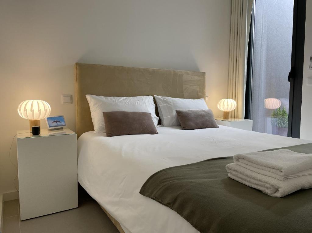 een slaapkamer met een groot wit bed met 2 lampen bij Aldoar House in Porto
