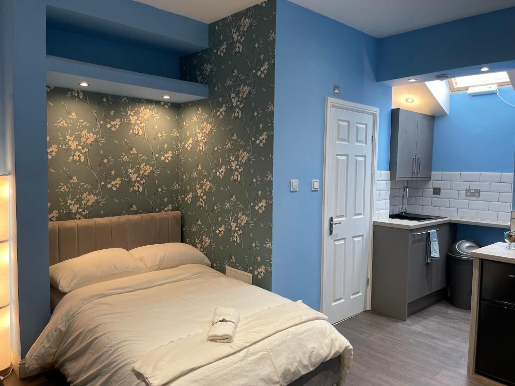 - une chambre avec un lit et un mur bleu dans l'établissement Cosy Studio in Heart of London, à Londres