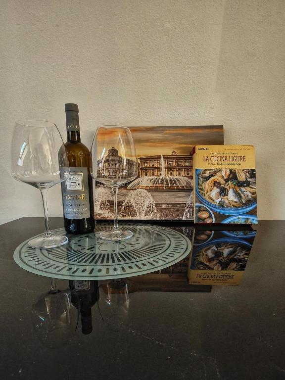 a bottle of wine and two wine glasses on a table at La Mansarda del Principe, vicoli, acquario e lanterna in Genoa