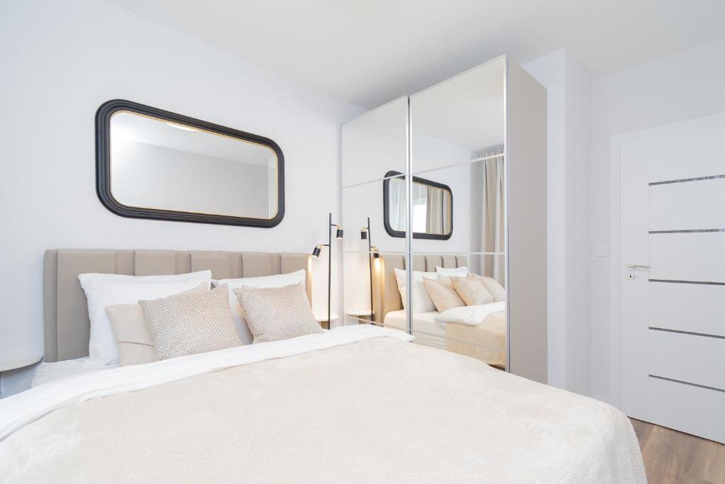 a bedroom with a large white bed and a mirror at Glow Apartments, Letnica - Apartamenty Bursztynowa Zatoka&Przystań Letnica in Gdańsk