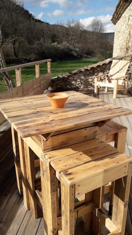 una mesa de madera en una terraza con un tazón en Les Gîtes du Saro, en Chabestan