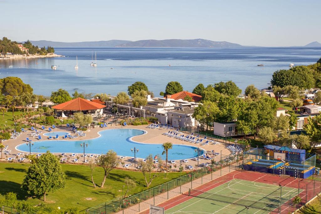 a resort with a large swimming pool next to the water at Camping Residence Oliva in Rabac