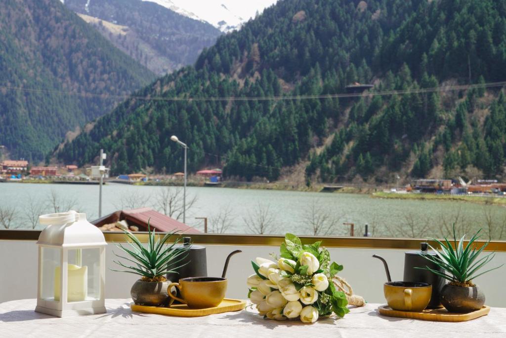 een tafel met bloemen en kopjes en uitzicht op een berg bij UZUNGÖL ADİLOGLU SUIT in Uzungol