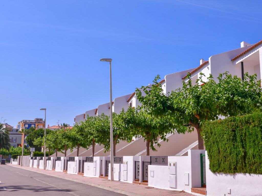 ein Gebäude mit weißen Türen und Bäumen auf einer Straße in der Unterkunft Belvilla by OYO Apartment in Torreblanca in Torreblanca