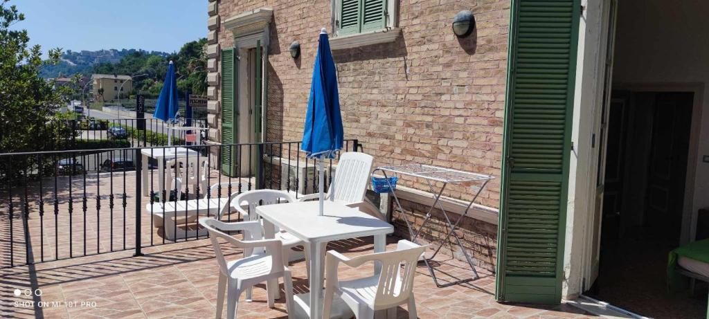 une terrasse avec des chaises blanches, une table et un parasol dans l'établissement Casa Lucia, à Cupra Marittima