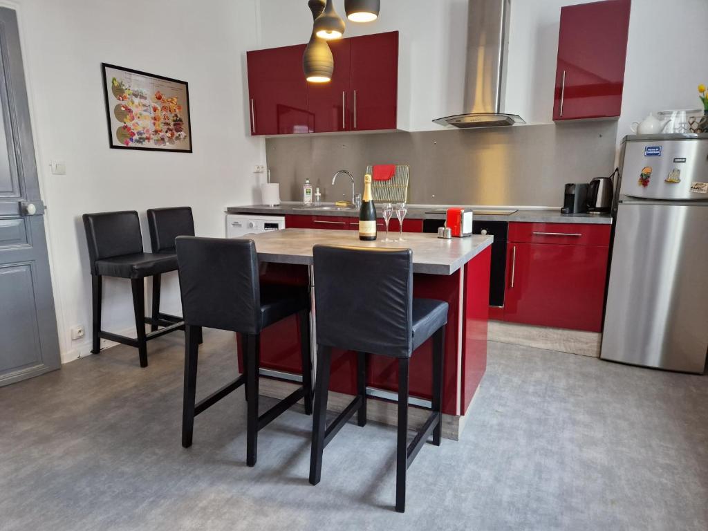 une cuisine avec des placards rouges et une table avec des chaises dans l'établissement Hypercentre Epernay appartement 4 pers The Clubhouse, à Épernay
