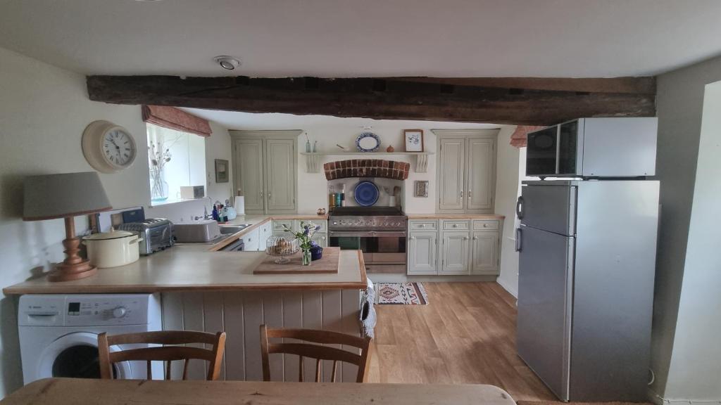 a kitchen with a refrigerator and a table with chairs at Characterful Cotswold cottage in Cirencester