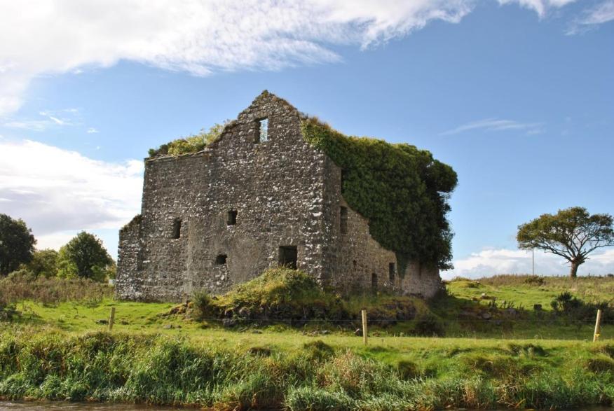 an old stone building on a grassy field at Apartment in milltown in Galway