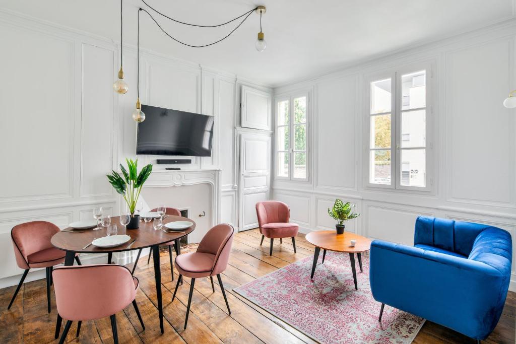 uma sala de estar com uma mesa e cadeiras e uma televisão em Cervantes - Le 31bis em Rennes