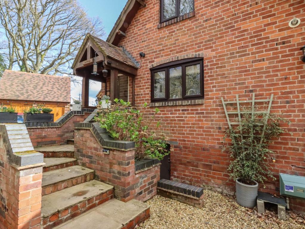 uma casa de tijolos com escadas e vasos de plantas sobre ela em Beau Cottage em Bewdley