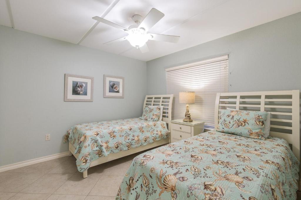 1 dormitorio con 2 camas y ventilador de techo en Surfside II #109 home, en Coffeyville