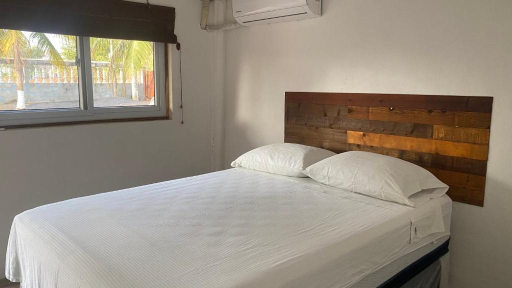 a bedroom with a white bed with a wooden headboard at Coco Beach in El Paredón Buena Vista