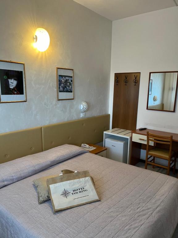 una habitación de hotel con una cama con un libro encima en Hotel Touring, en Sottomarina