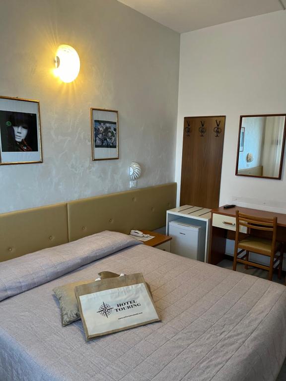 una camera d'albergo con un letto e un libro sopra di Hotel Touring a Sottomarina