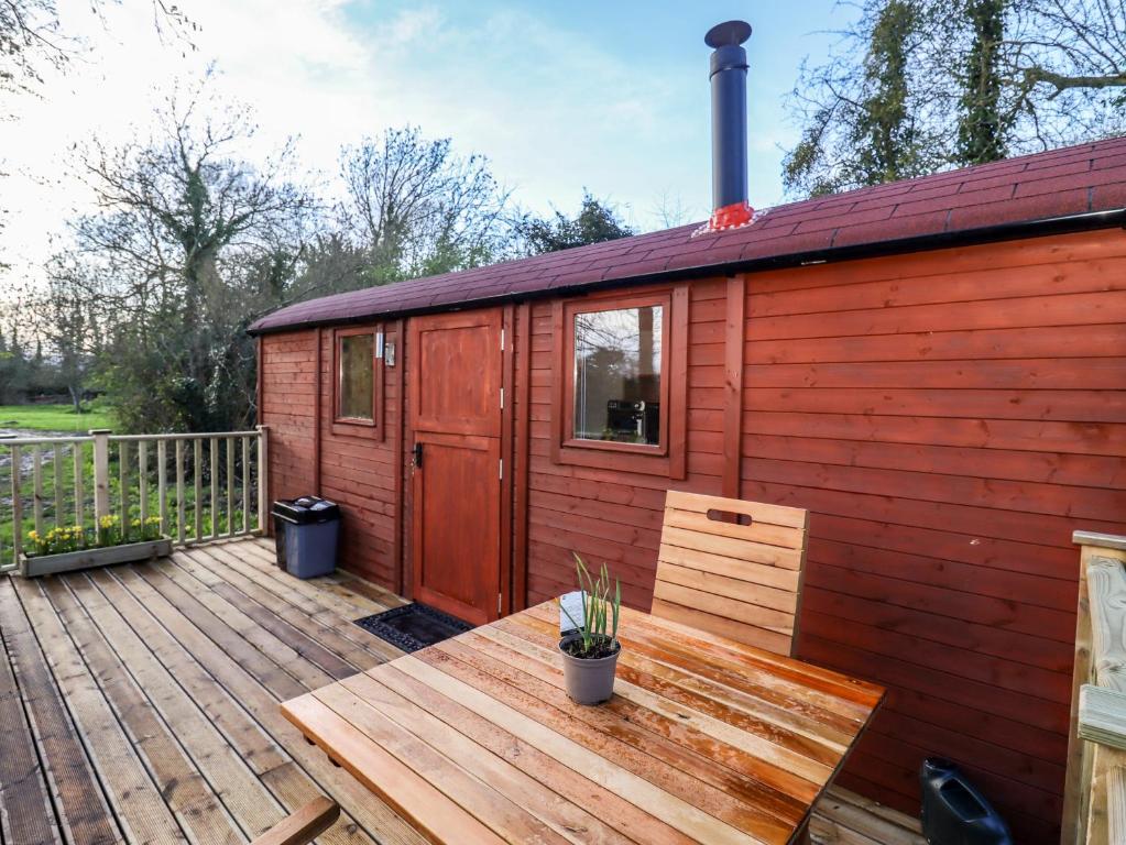 a red cabin with a bench on a deck at The Foxes Den Shepherds Hut in Bristol