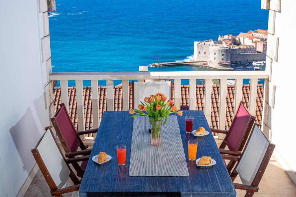 una mesa azul con un jarrón de flores en el balcón en Apartments Mariana, en Dubrovnik