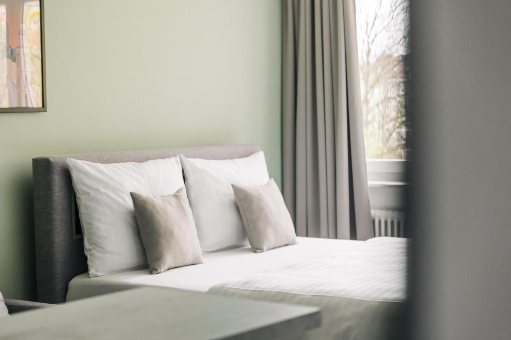 a bed with white pillows in a room with a window at Homaris Apartments Frankfurt in Frankfurt
