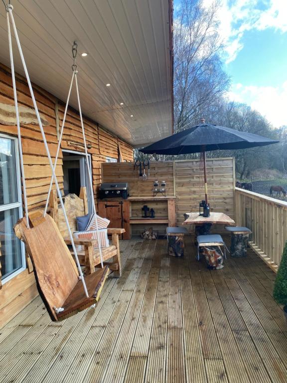 a porch with a swing and a table and an umbrella at Devon River Glamping Pods in Alloa