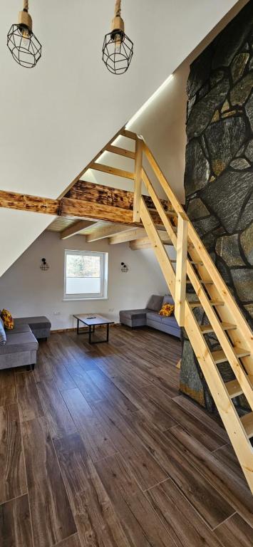 a large living room with a stone wall and stairs at Sylwia Aparthouse - Biały Dunajec in Biały Dunajec