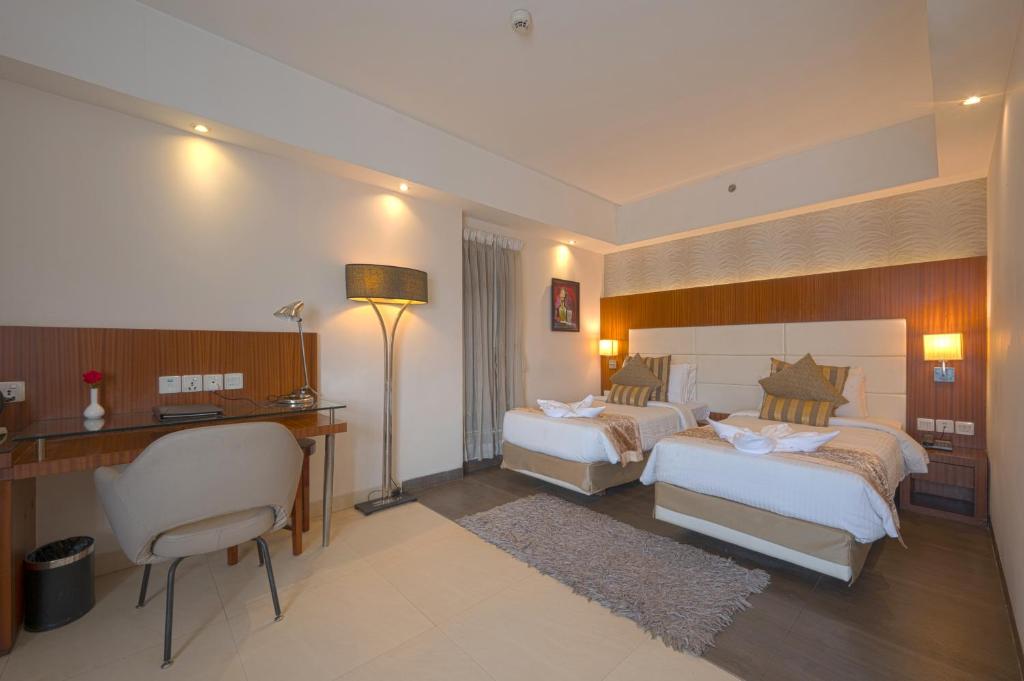 a hotel room with two beds and a desk at Celesta - Kolkata in Kolkata