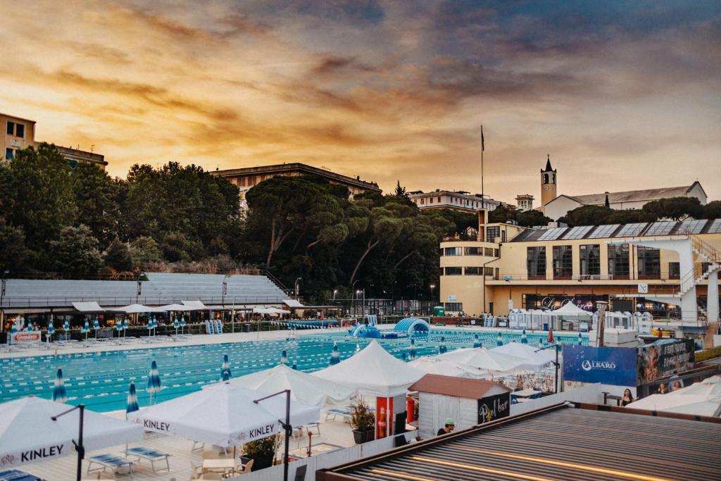 a large swimming pool with white umbrellas and buildings at Arena Albaro House in Genova