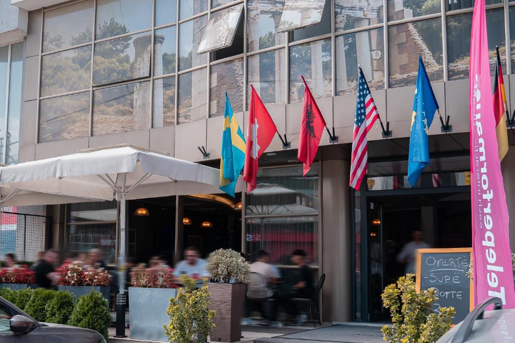 een groep vlaggen voor een gebouw bij Hotel Apollonia in Gjakove