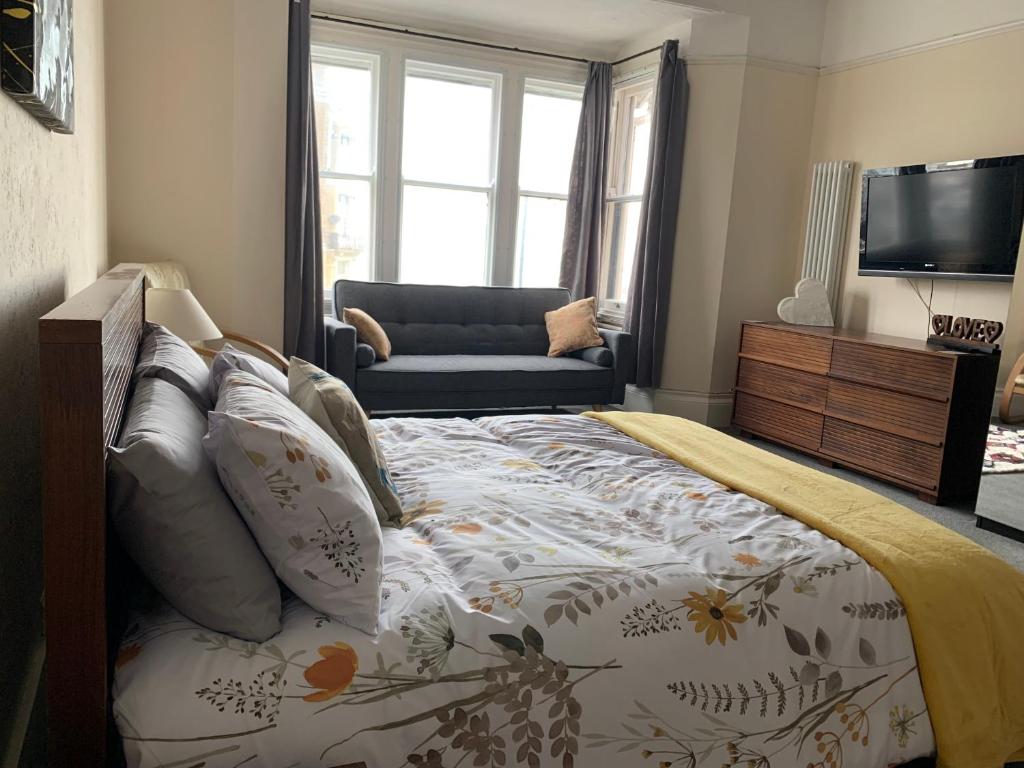 a bedroom with a bed and a couch and a television at Ocean view double with ensuite, with access to private garden and bike store in Kent