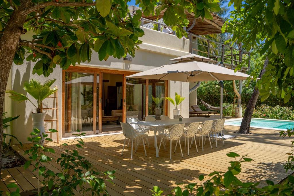 a patio with a table and chairs and an umbrella at Zanzibar White Sand Luxury Villas & Spa - Relais & Chateaux in Paje