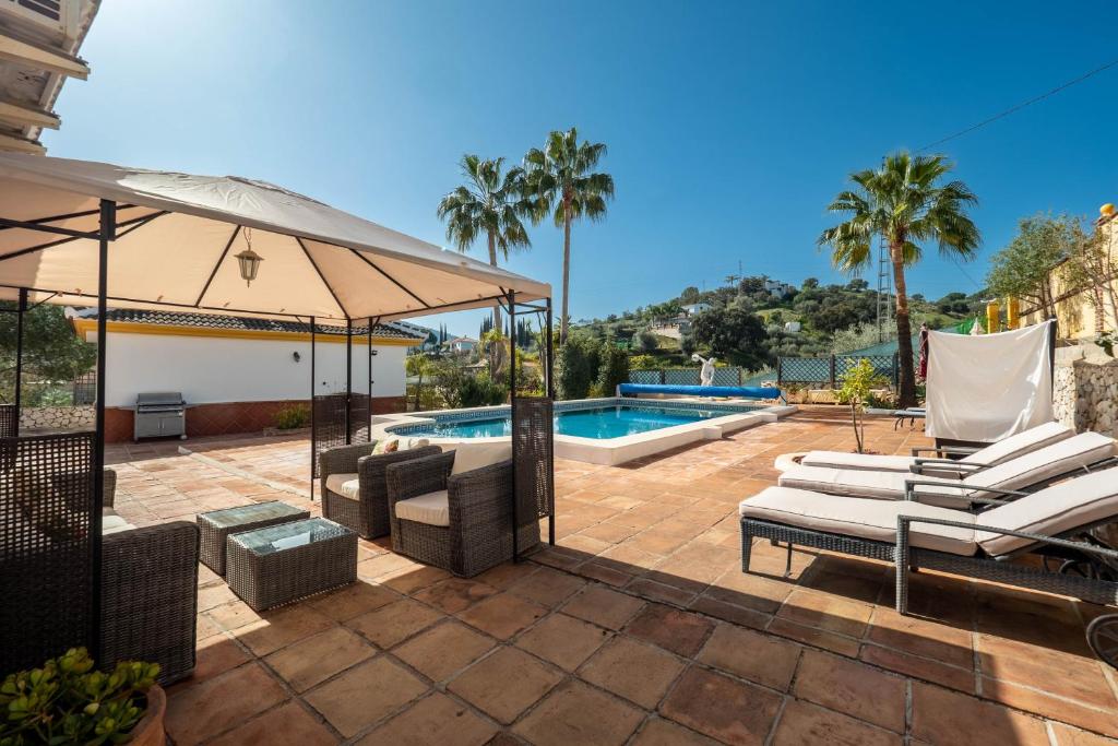 a patio with lounge chairs and a swimming pool at Casa Amarilla Casitas in Alhaurín el Grande