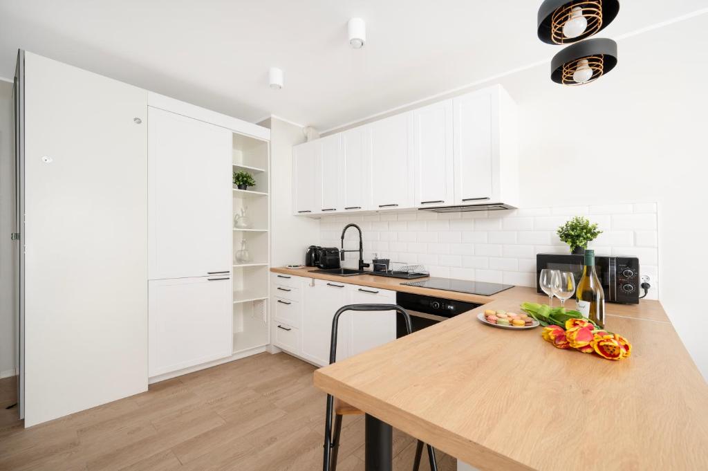 a kitchen with white cabinets and a wooden counter top at Hideaway Apartment - Terrace with Garden & Parking- by Rentujemy in Łódź