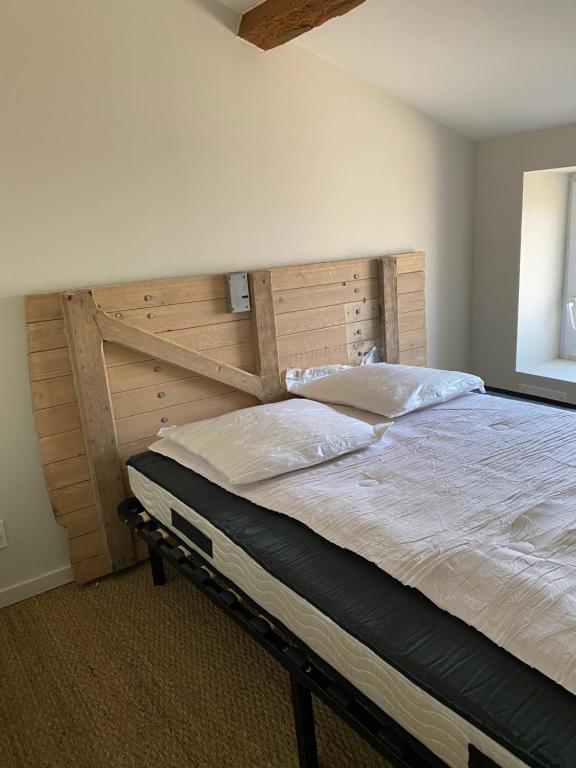 une chambre avec un grand lit avec une tête de lit en bois dans l'établissement Chambre 2, à Oudon