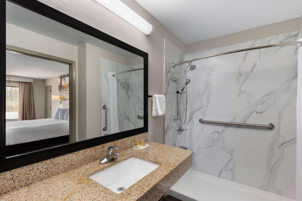 a bathroom with a sink and a shower with a mirror at Days Inn by Wyndham Childersburg in Childersburg