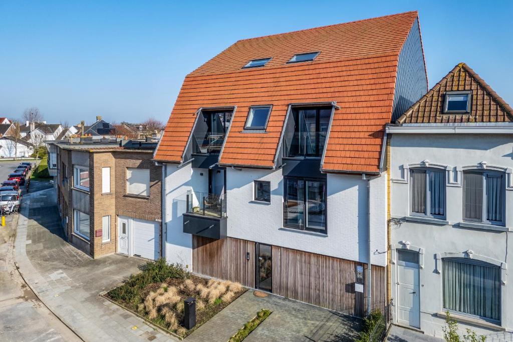 een afbeelding van een huis met een oranje dak bij Flat White - Luxe app aan zee met terras & parking in De Haan