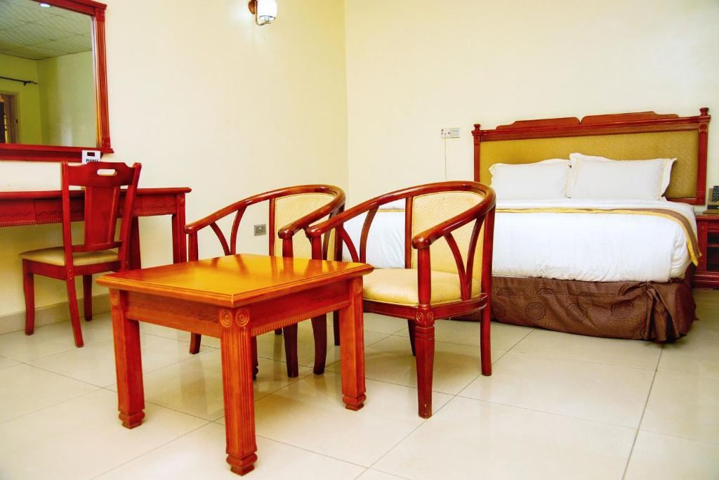 a bedroom with a bed and a table and chairs at Classicus Inn & Apartments in Ibadan