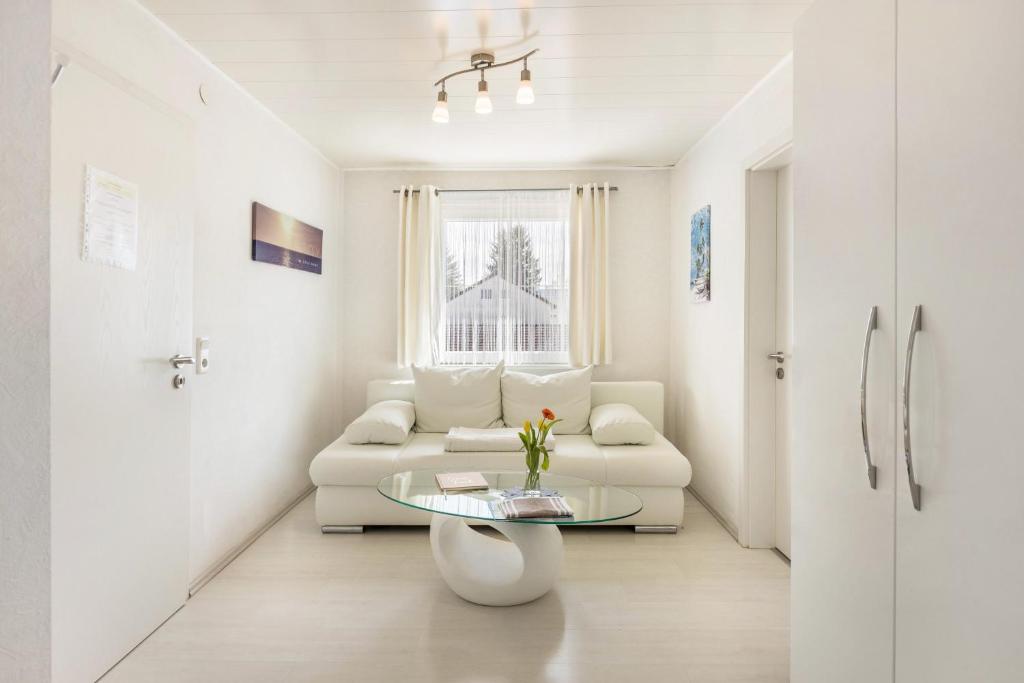 Sala de estar blanca con sofá y mesa de cristal en Apartment City, en Radolfzell am Bodensee