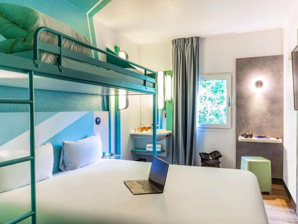 a bedroom with a bed with a laptop on it at ibis budget Marne la Vallée Chelles in Chelles