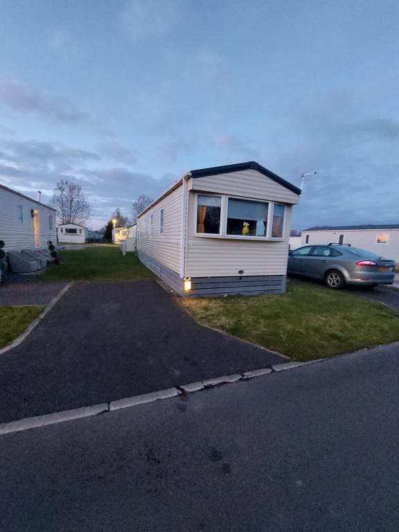 una casa pequeña en un estacionamiento con un coche en regent bay, en Morecambe