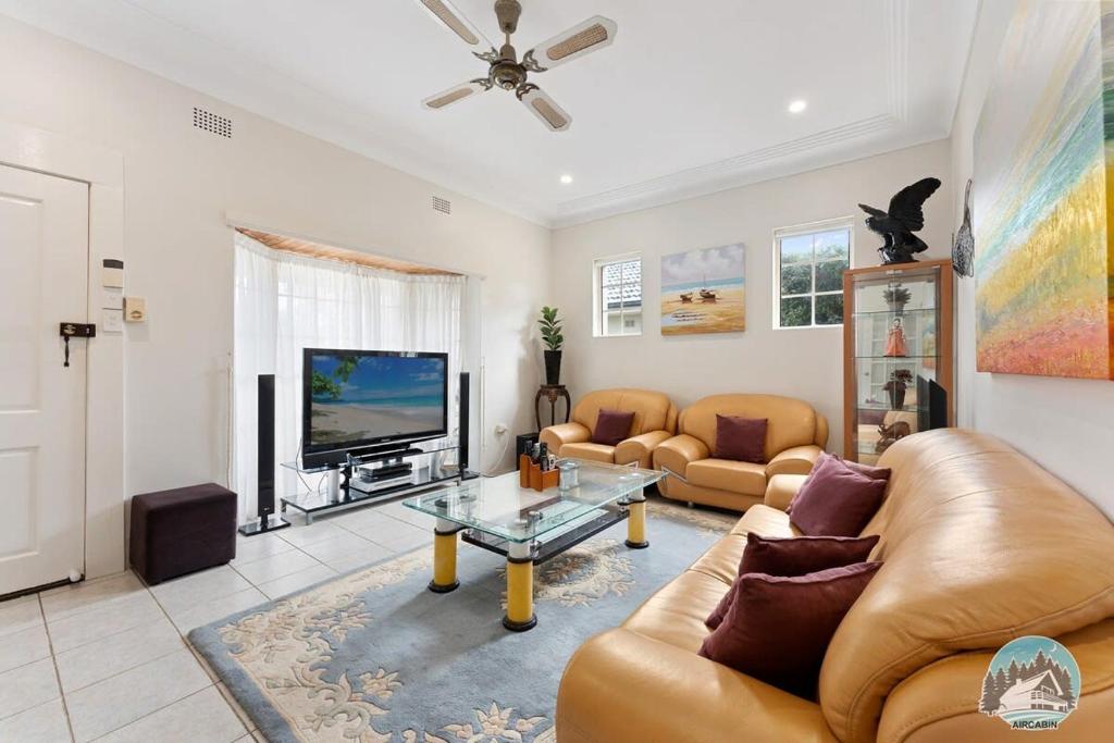 a living room with couches and a flat screen tv at Aircabin - Blakehurst - Spacious - 5 Beds House in Sydney