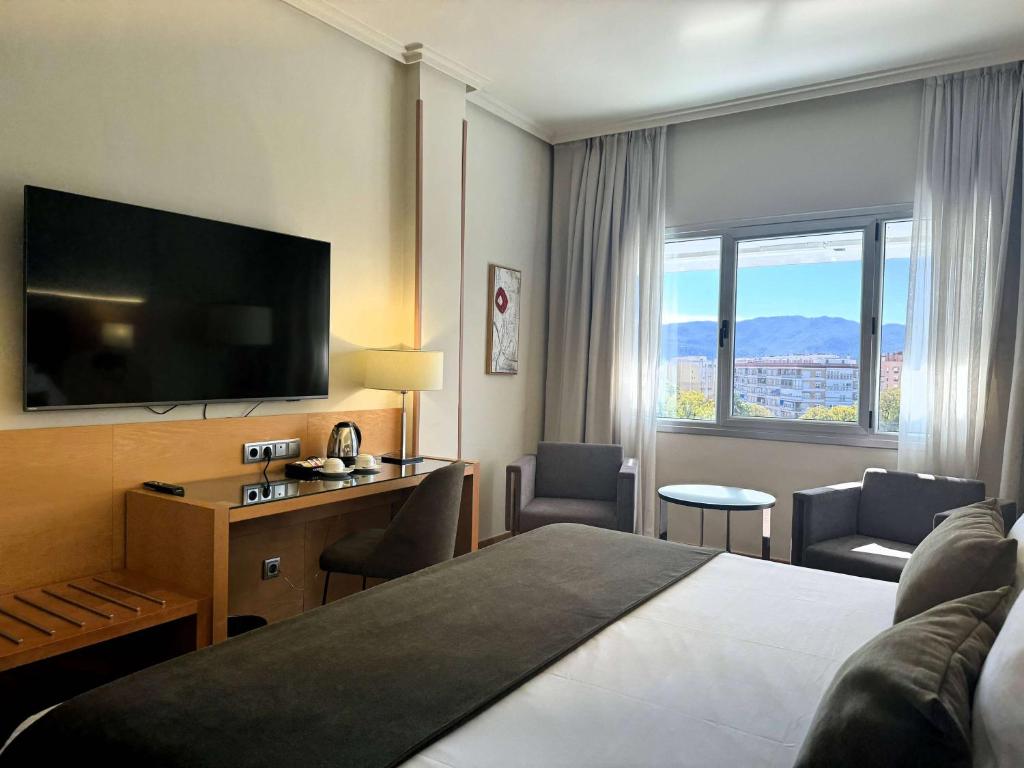 a hotel room with a bed and a flat screen tv at Barceló Murcia Siete Coronas in Murcia