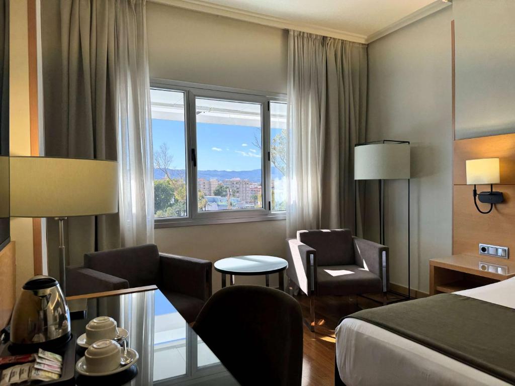a hotel room with a bed and a table and chairs at Barceló Murcia Siete Coronas in Murcia