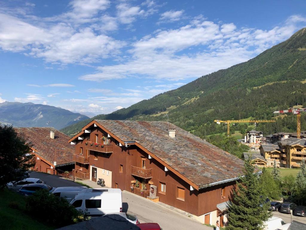a large brown building with mountains in the background at Pied des pistes - Très bel appartement 4 personnes in Valmorel