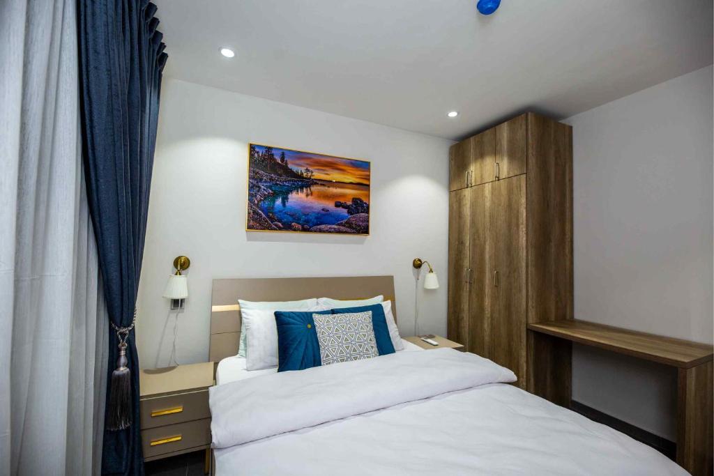 a bedroom with a white bed with blue pillows at Park Apartments in Accra