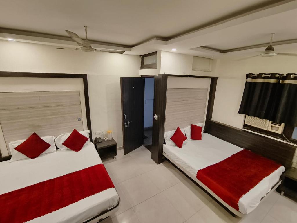 two beds in a room with red pillows at Hare Krishna Main Bazar in New Delhi