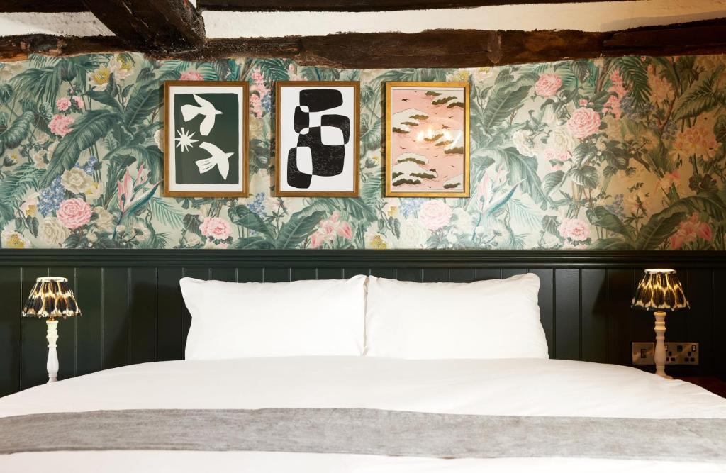 1 dormitorio con cama y papel pintado con motivos florales en Narborough Arms, en Narborough
