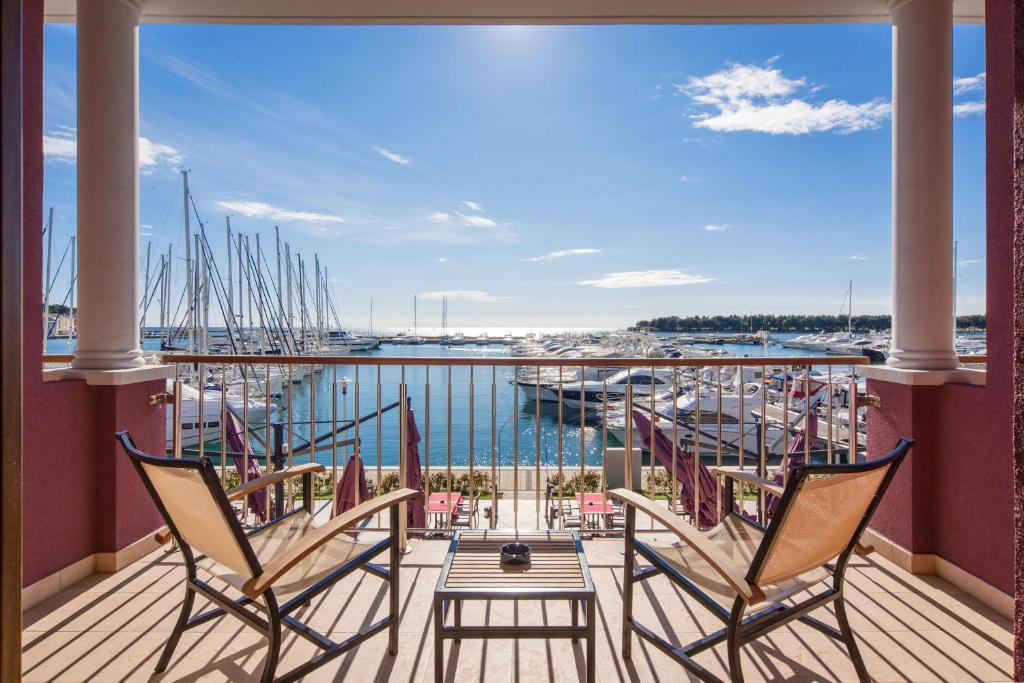 een balkon met 2 stoelen en een tafel en een jachthaven bij Hotel Nautica - Wellness & SPA, Free parking, Pet friendly in Novigrad Istria