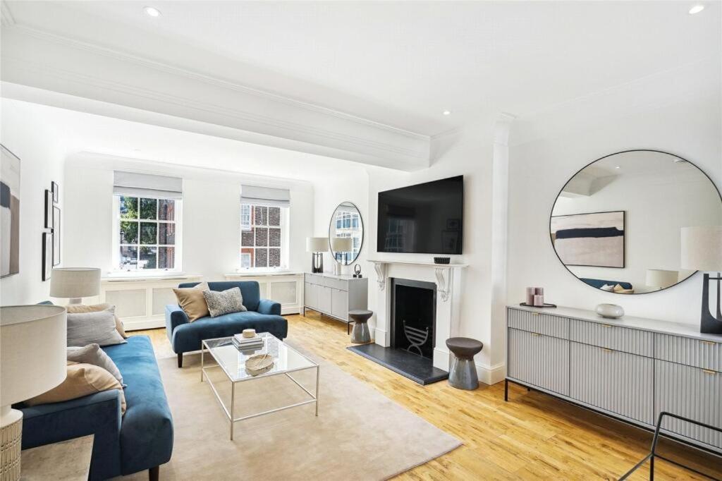 a living room with a blue couch and a mirror at 4 bedroom home by Buckingham Palace in London