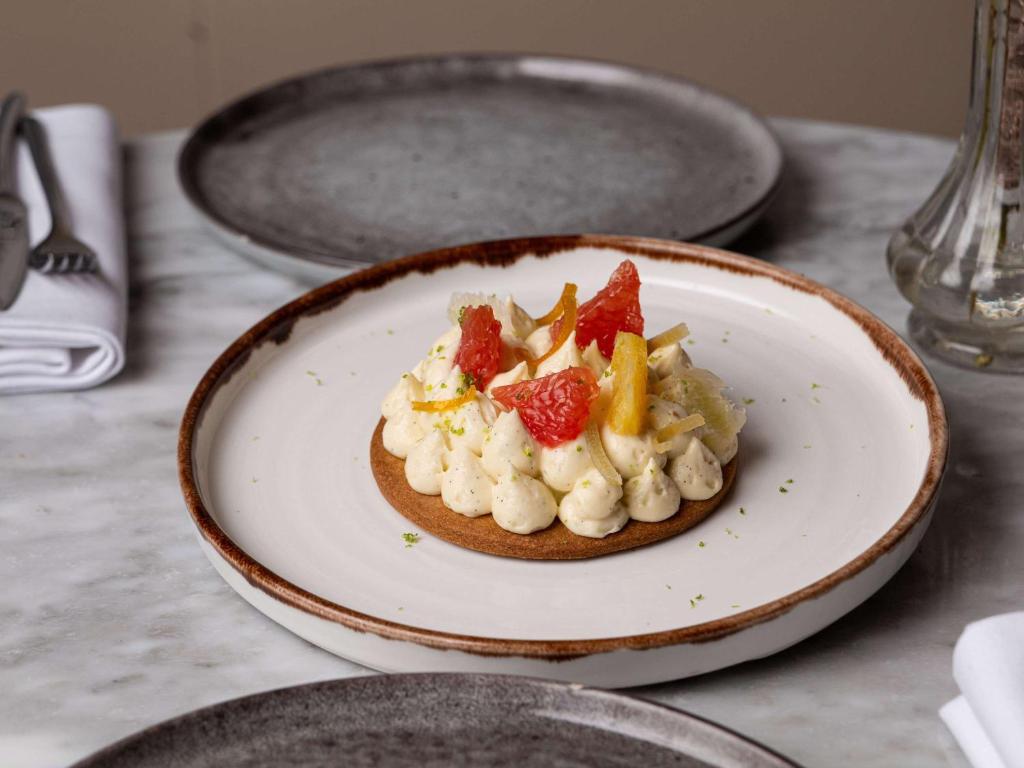 a plate of food with fruit on a table at The 1932 Hotel & Spa Cap d'Antibes - MGallery Collection in Juan-les-Pins